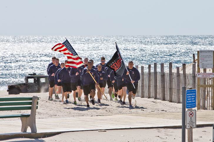 Seaside Park, N.J. – Twelve active-duty Marines from McGuire Air Force Base/Fort Dix stormed up the Seaside Park beach with the mission to deliver the inaugural Seaside Semper Five Marine Corps Charity 5k Run/Walk race t-shirt to Seaside Park Mayor Robert Matthies and Rear Admiral Mo Hill. The race, which will take place on September 13th of this year, will benefit the MARSOC Foundation (United States Marine Corps Special Operations Command). Participants can register now at www.RaceForum.com/SemperFive. (Photo credit: Francis Costello)